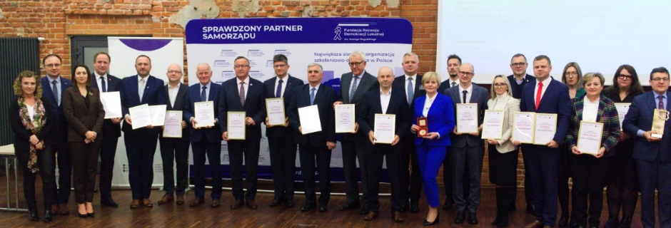 Grupa mężczyzn i kobiet z dyplomami ustawieni w szeregu
